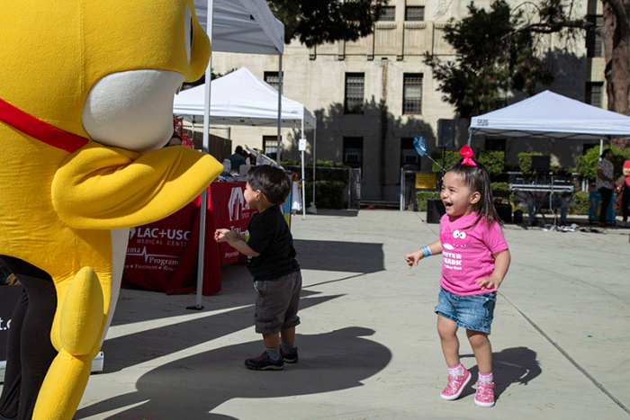 Little girl at LAC+USC Kidz Health Fair playing with giant stuffed animal