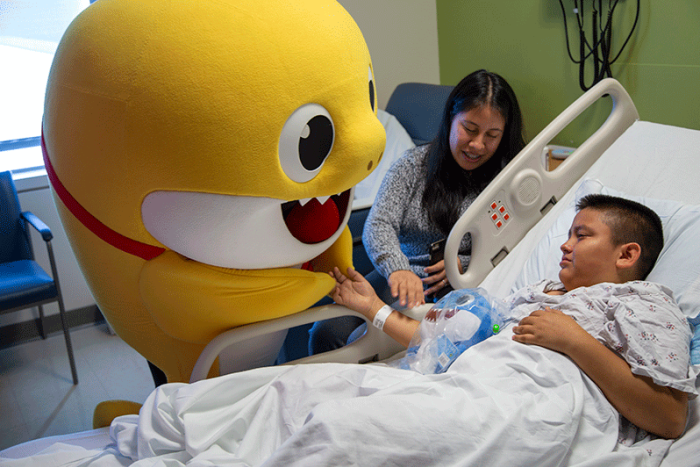 Large babyshark visiting boy in hospital bed