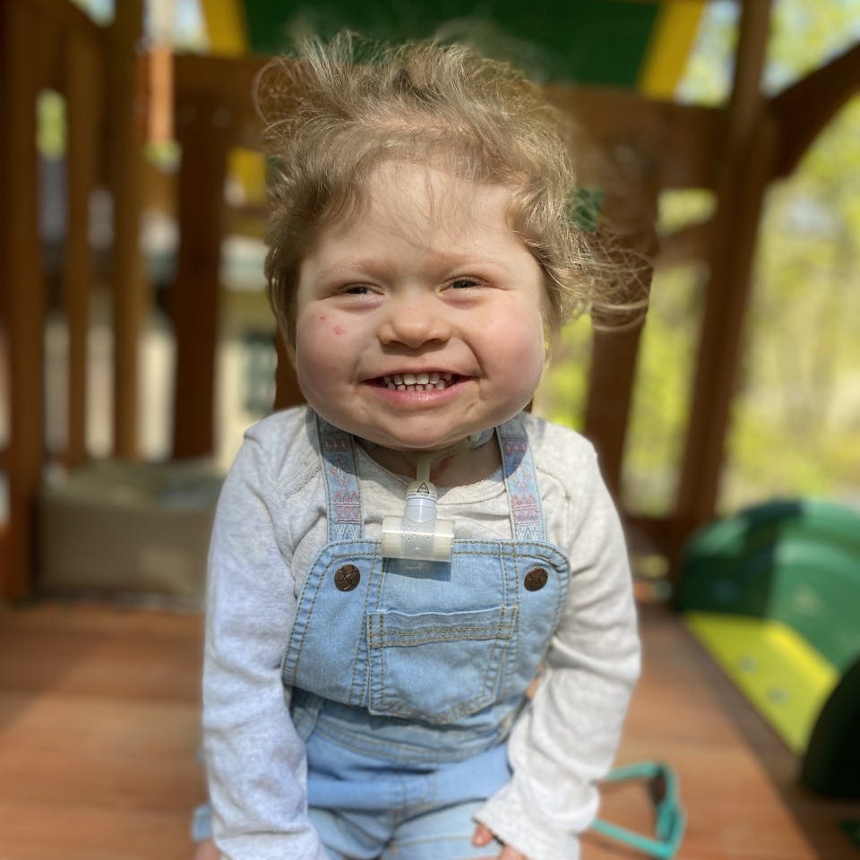Tessa, age 2, congenital heart defect, smiling siting outside